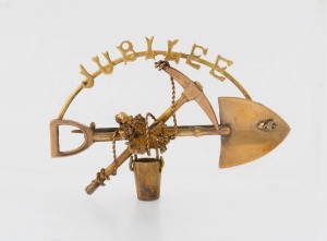 A 9ct gold miner's brooch with crossed pick and shovel emblazoned "JUBILEE", stamped "9ct", 4.5cm wide, 4.75 grams total