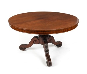 An antique Australian cedar tilt-top supper table with two piece book matched well figured top, cross banded edge and skirt supported on a turned pedestal with lotus carved collar and impressive scroll and lambs tongue cabriole legs with recessed brass castors, circa 1850, 72cm high, 124cm diameter