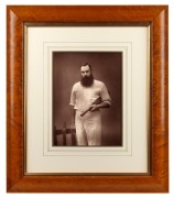 W.G. GRACE, posing in his cricket whites with a bat under his arm, the portrait by Herbert Rose Barraud, circa 1885; framed and glazed, overall 48 x 41cm.
