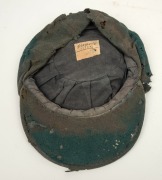 BILL JOHNSTON'S AUSTRALIAN 1947-48 BAGGY GREEN TEST TEAM CAP, green wool with embroidered Australian cost-of-arms and the dates "1947-48"embroidered to the front panel; "Farmers Sydney" label to the inside crown. Poor condition. Bill Johnston played in 4 - 6