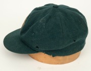 AN AUSTRALIAN TEST TEAM BAGGY GREEN dated "1956" (player unknown), green wool with the Australian coat-of-arms and the year "1956" embroidered to the front panel. Fairly good condition but with some holes/wear to the left and rear of the cap.&nbsp;Provenance: - 5