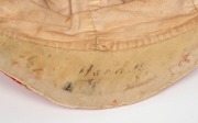 A TASMANIAN COLONIAL CRICKET CAP from the late 19th Century, red with white piping, a button-down peak, and with an illegible signature under the brim. Although worn in places, in remarkably good condition for one of the oldest surviving Australian cricke - 6