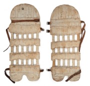 A pair of late-nineteenth century match-used "skeleton" open-ribbed cane and leather cricket pads, with leather straps and buckles. (2). Each approx. 67cm.
