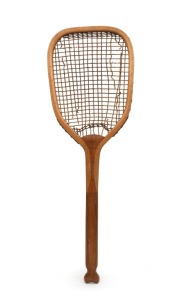 "THE DEMON" TENNIS RACQUET WITH A FISHTAIL HANDLE: a wooden tennis racquet with gut strings, circa 1890s made by Slazenger. The racquet head is a rounded triangular shape, with a transitional flat-top. At the throat, there is a solid wood convex wedge tha
