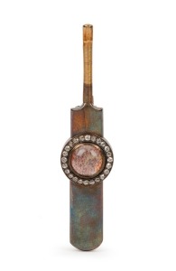 THE BLACKHAM BROOCH, a piece of the original 'Blackham Ball' used by Frederick Spofforth during the first Ashes Test against England in London in 1882; inset under a rock crystal dome within a circlet of 24 old-cut diamonds and mounted in a 15 carat yellow gold cricket bat-shaped brooch