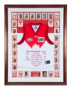 A Sydney Swans 2005 Premiership souvenir display comprising of a Swans jersey with the names and positions of the Premiership Team embroidered on the front surrounded by 21 signed cards and other unsigned cards, together with a plaque describing the four - 2