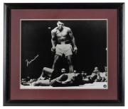 MUHAMMAD ALI: Signed black and white photograph of Ali standing over Sonny Liston, window mounted, framed and glazed with CofA verso, overall 61 x 71cm.