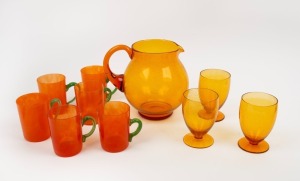 A vintage amber glass water jug and three matching goblets all with speckle&nbsp;inclusions; together with six orange cloud glass mugs with applied green handles, circa 1950, the jug 18cm high