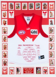 A Sydney Swans 2005 Premiership souvenir display comprising of a Swans jersey with the names and positions of the Premiership Team embroidered on the front surrounded by 21 signed cards and other unsigned cards, together with a plaque describing the four 