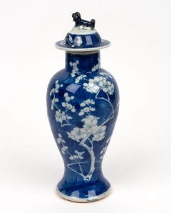 A Chinese blue and white lidded vase with blossom decoration and foo dog finial, 19th/20th century, blue underglaze four character mark to base, 27cm high