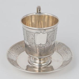 An antique Russian silver vodka cup and saucer with bright cut engraved decoration. Atelier mark for S.M.&nbsp;Ikonikov of Moscow, 1876, (2 items), 8.5cm high including, 128 grams total.