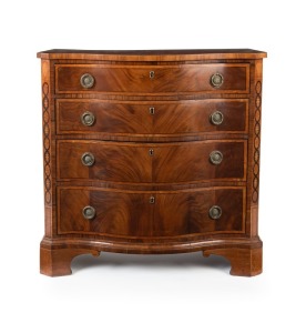 An antique George III Sheraton period serpentine fronted bachelor's chest with four graduated drawers book matched in flame mahogany with satinwood banding and ebony stringing; the canted corners with oval marquetry inlays in satinwood; rosewood cross ban
