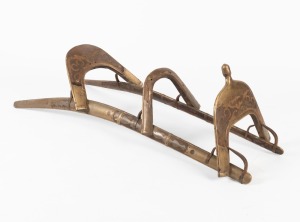 An antique Egyptian dromedary camel saddle with teak frame, decorative brass inlay, strap work and iron bracket supports, early 20th century, 39cm high, 136cm long, 48cm wide.