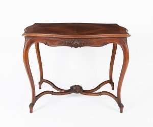 An antique French serpentine occasional table with quarter book matched walnut veneered top, cross banded edge and carved floral frieze standing on slender cabriolet&nbsp;legs united by a carved cross frame stretch, circa 1890, 78cm high, 98cm long, 66cm deep.