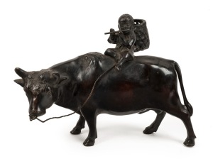 A Chinese cast bronze statue of a boy with flute sitting on an ox, 19th/20th century, ​​​​​​​23cm high, 32cm long