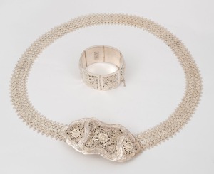 A vintage Thai 800 silver filigree belt buckle with floral decoration and studded lace belt, together with a Thai hinged panel bracelet. 20th century.The belt 92cm long. 440 grams total.