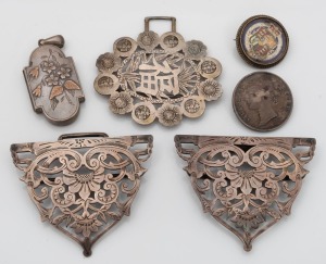 An antique silver locket with rose gold highlights, two antique English silver coin brooches, a sterling silver belt buckle, plus a Chinese silver buckle end, 19th/20th century, (5 items), the locket 5.5cm high including bow, 80 grams total.