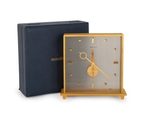 JAEGER LE COULTRE&nbsp;mantle clock in gilded brass case with reeded frosted lucite back supporting the dial with gilt hands and block baton numeral.&nbsp;Skeletonised&nbsp;gilt inline&nbsp;movement, jewelled,&nbsp;with balance wheel, lever escapement and going barrel. Housed in 