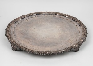 An antique English Sheffield plate salver in the Geo III style. Rococo shell and acanthus scroll edge with pie crust border, flower and leaf hand engraved decoration with central armorial of a hound engraved 'KEEP FAITH', circa 1890, 60cm diameter.