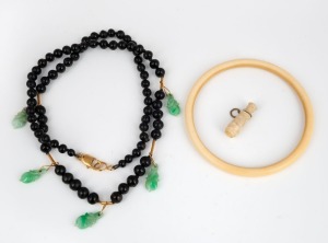 A vintage carved ivory bangle, carved ivory charm, and a black bead necklace with Chinese carved jade drops, 19th/20th century, (3 items), ​​​​​​​the bangle 7.5cm diameter