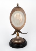 An antique emu egg ornament with carved lyrebird cartouche on silver plated fern mounts on turned ebonized timber base, circa 1900, ​​​​​​​24cm high