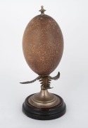 An antique emu egg ornament with carved lyrebird cartouche on silver plated fern mounts on turned ebonized timber base, circa 1900, ​​​​​​​24cm high - 2