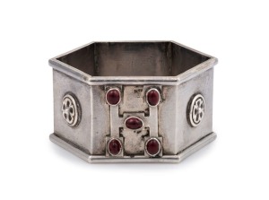An exceptional antique Australian silver napkin ring of hexagonal Gothic form adorned with floral rosettes and "H" ownership monogram studded with five cabochon rubies, 19th/20th century, stamped "ST. SILVER, J.W.R.L. & A.G.", 4.5cm wide, 36 grams.