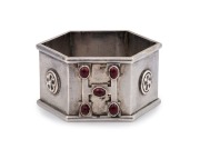 An exceptional antique Australian silver napkin ring of hexagonal Gothic form adorned with floral rosettes and "H" ownership monogram studded with five cabochon rubies, 19th/20th century, stamped "ST. SILVER, J.W.R.L. & A.G.", ​​​​​​​4.5cm wide, 36 grams.