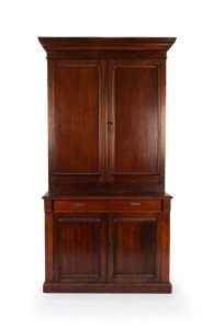 An antique Australian cedar bookcase with blind panelled doors (top and bottom) and two drawers with brass swing handles, red pine secondary timbers, 19th century, 240cm high, 128cm wide, 49cm deep
