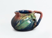 REMUED&nbsp;pottery jug with applied gumnuts, branch handle and leaf, glazed in pink, blue and green, incised "Remued, Hand Made, 173SM", 7cm high, 12cm wide