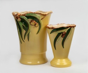 DIANA WARE graduated pair of yellow ceramic vases decorated with gumnuts and leaves, the smaller example with circular factory mark to base, the larger 22cm high