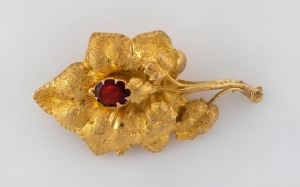 An antique Colonial Australian 15ct gold brooch with floral motif, set with a red stone, circa 1870s, 4.1cm wide, 4.1 grams.