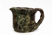 ARTIST UNKNOWN green glazed hand-built pottery jug with applied figures in landscape, in the manner of Jolliff, ​​​​​​​14cm high