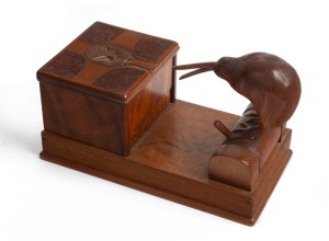 A New Zealand novelty cigarette dispenser, crafted from native timbers and paua shell with kiwi and Tiki decoration, 20th century, 20cm wide