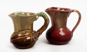REMUED green and brown glazed pottery jug with applied gumnuts, leaf and branch handle, incised "Remued"; together with a PAMELA (attributed) pink glazed pottery jug with yellow highlights, (2 items), 11cm and 11.5cm high