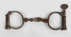 155 · Antique handcuffs with remains of nickel plated finish and screw key, 19th century, ​​​​​​​26cm wide.