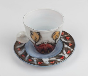 MICHAEL AQUINO hand-painted Australian art glass cup and saucer, the saucer 15.5cm wide