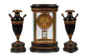 An antique French three piece library clock set, oval cased four glass clock with applied ormolu floral decoration and black patinated plinth with match top, the urn side pieces similarly decorated, time and gong striking eight day movement with mercury filled pendulum, circa 1870, 32cm high