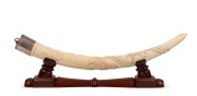 A pair of carved African ivory tusk ornaments mounted in sterling silver and presented on later carved timber stands, 60cm each