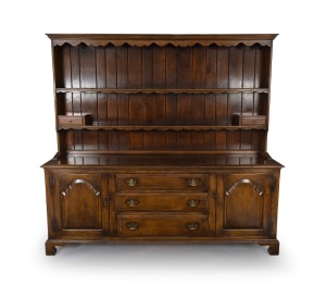 A good quality vintage oak dresser base and rack in the antique Welsh manner with fielded panel doors flanking three graduated drawers standing on bracket feet, 20th century, 186cm high, 200cm wide, 51cm deep