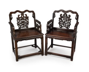 A pair of antique Chinese rosewood hall armchairs, pierced and carved floral back splats, scroll carved frieze standing on cross stretcher bases, circa 1910, 99cm high, 59cm across the arms