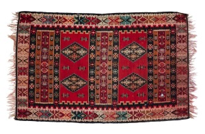A tribal flat weave rug with red and black ground with green highlights, 215 x 132cm