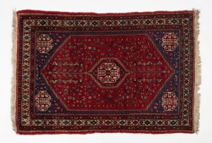 A small hand-knotted wool rug on crimson and beige ground, ​​​​​​​165 x 82cm.