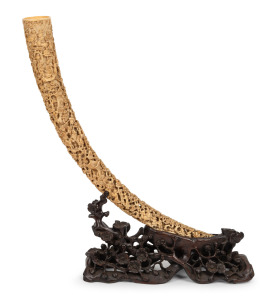A fine and impressive antique Chinese carved ivory tusk displayed on original rosewood table stand, Qing Dynasty, 19th century, 60cm high, 48cm wide overall