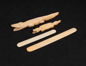 An African carved ivory double ended crocodile fetish figure, an African carved hippopotamus tooth crocodile ornament and two whalebone paper knives, 19th/20th century, (4 items), the largest 20cm long
