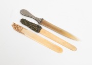 Three antique paper knives comprising of one with silver handle and horn blade, one carved bone and the other pressed metal and bone, 19th/20th century, the largest 22.5cm long