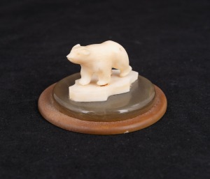 An Inuit carved marine ivory polar bear statue mounted on horn plinth, 20th century, 4cm high, 7cm diameter