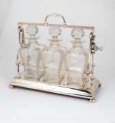 An antique English silver plated tantalus set, with three matching crystal decanters and original key, circa 1900, 34cm high, 38cm wide