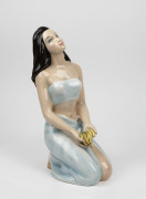 A vintage Italian porcelain statue of a kneeling woman offering a bunch of bananas, mid 20th century, ​​​​​​​signature to base (illegible), 39cm high.