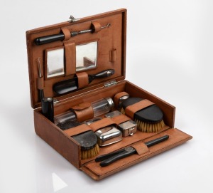 A travelling vanity set with ebony and silver plated accessories housed in a fitted tan leather case, 19th/20th century, the case 28cm wide